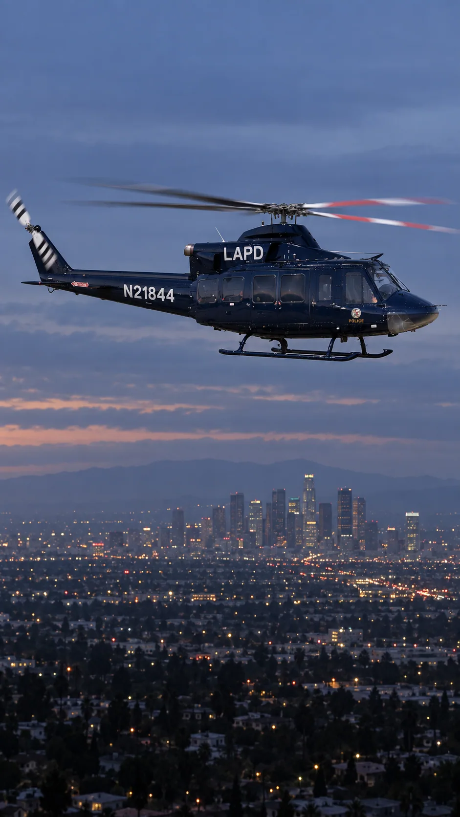 Illustration of N21844, a Bell 412EP of LAPD Air Support — over the Los Angeles basin at dusk.