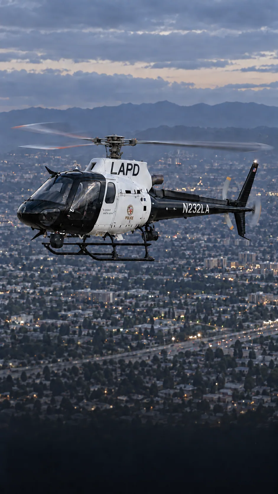 Illustration of N232LA, an Airbus AS350 B3 of LAPD Air Support — black and white LAPD patrol scheme — over the Los Angeles basin at dusk.