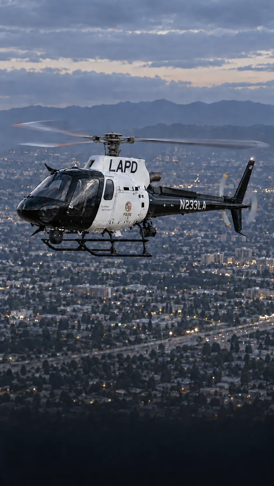 Illustration of N233LA, an Airbus AS350 B3 of LAPD Air Support — owner confirmed current N233LA black-and-white scheme matches N472LA, September 11 2026 — over the Los Angeles basin at dusk.