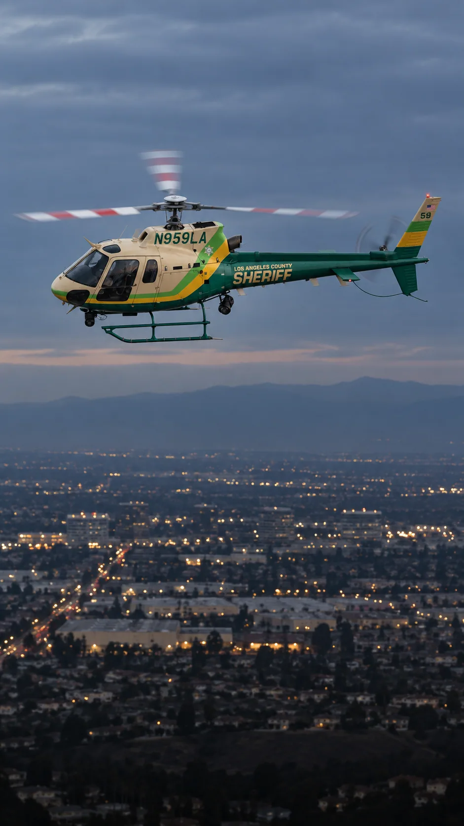 Illustration of N959LA, an Airbus AS350 of Sheriff Air Support — over the Los Angeles basin at dusk.