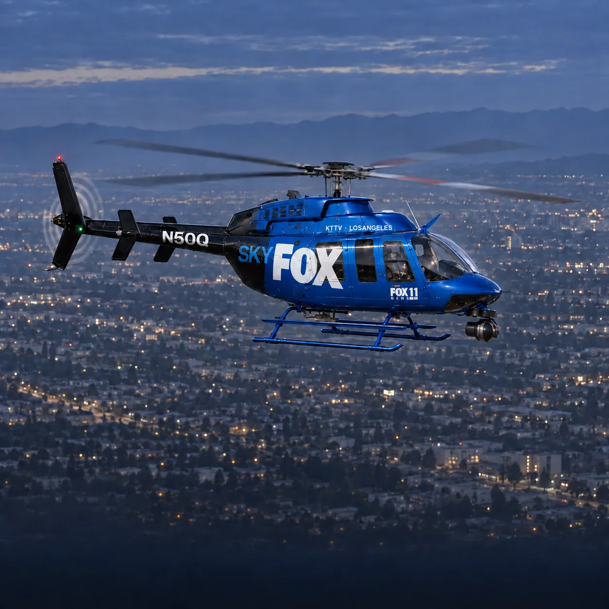 Illustration of the shared SkyFOX 11 / SkyCAL Bell 407 news helicopter, registration N50Q, showing its blue and black SkyFOX side over Los Angeles at dusk.
